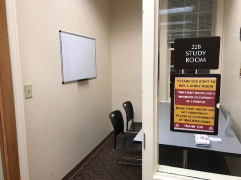 Small room with 2 chairs, table, whiteboard, and a window.