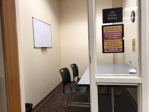 Small room with a white board, table, and two chairs.