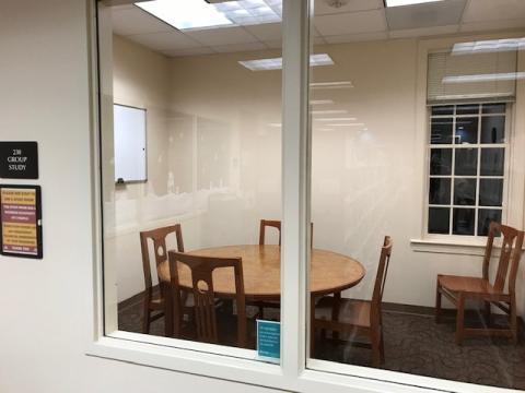 Group meeting room with a round table with 4 chairs and 2 additional chairs in the corners. Room has a window.